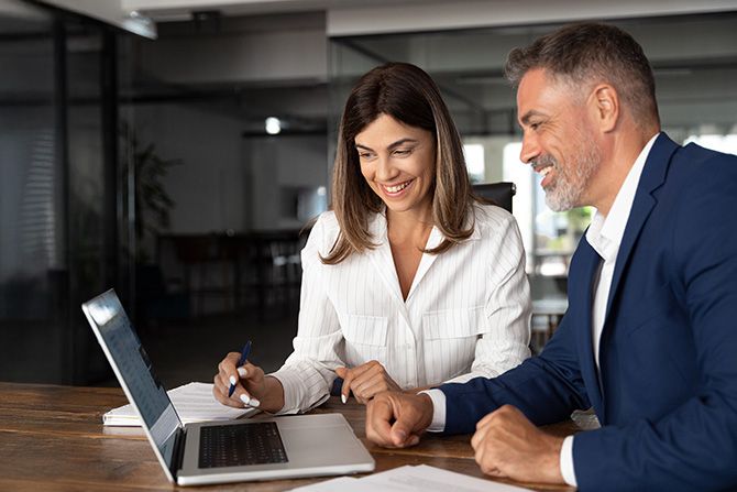 Man and woman in office looking at a laptop screen together