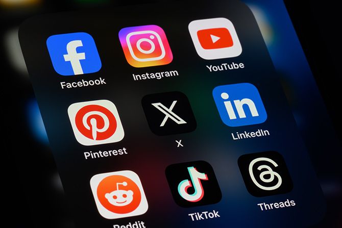 Promoting the Profession; Alt text: Close-up of a smartphone screen showing social media app icons, including Facebook, Instagram, YouTube, Pinterest, X, LinkedIn, Reddit, TikTok, and Threads, arranged in a grid. The image conveys digital connectivity and communication.